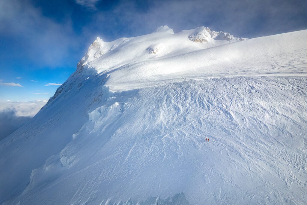 a man riding skis down the side of a snow covered slope