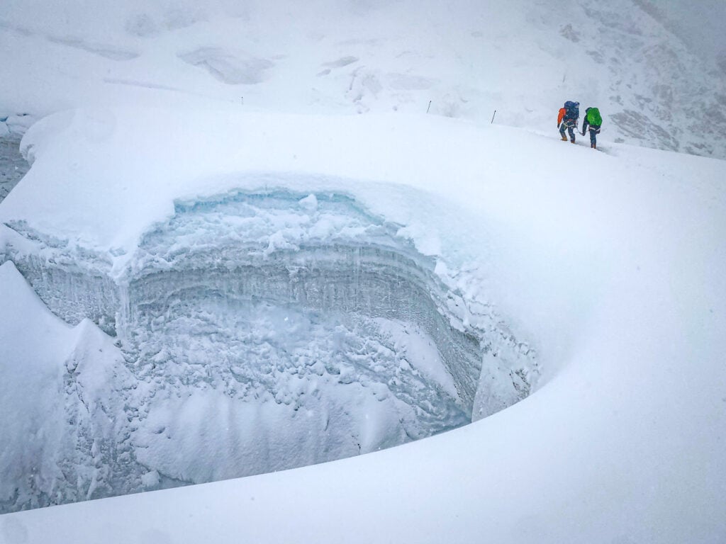 a couple of people standing on top of a snow covered slope