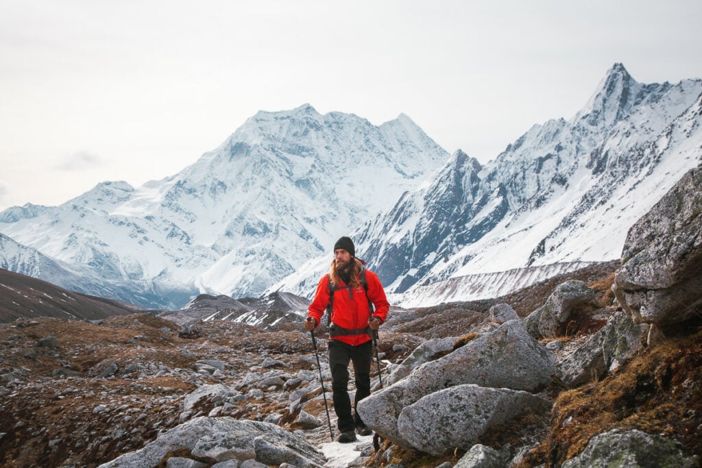 a man in a red jacket hiking up a mountain
