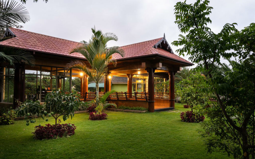 a house with a red roof sitting in the middle of a lush green yard